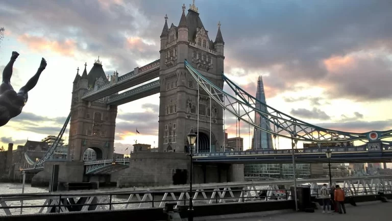 View of London’s Tower Bridge at sunset, with a diver statue in the foreground