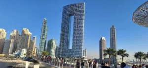 Moderni stolpičasti nebotičniki in obalna promenada v Abu Dhabiju ob jasnem, modrem nebu.