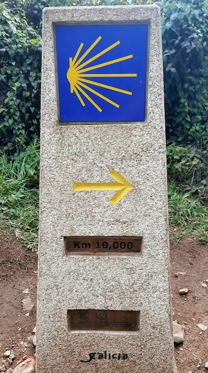 Camino smerokaz: školjka in rumena puščica na kamnitem mejnem stebru